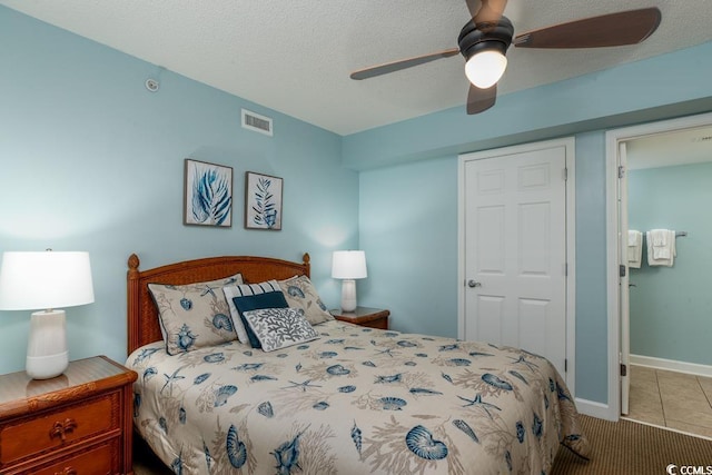 bedroom with tile patterned floors, visible vents, a ceiling fan, a textured ceiling, and baseboards