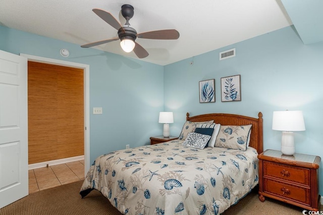 bedroom featuring tile patterned flooring, visible vents, and a ceiling fan