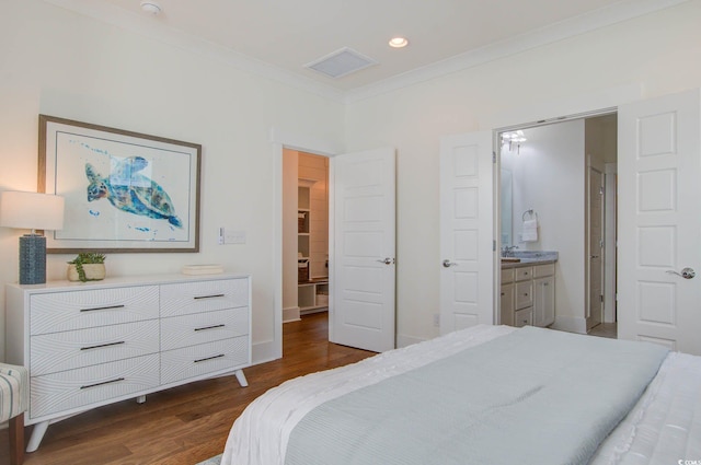 bedroom with connected bathroom, dark hardwood / wood-style floors, and crown molding