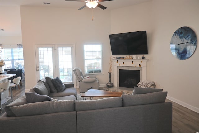 living room featuring wood-type flooring, a high ceiling, and ceiling fan