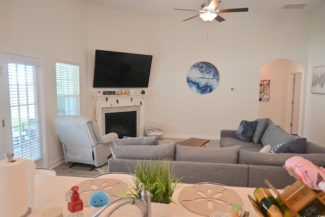 living room with a premium fireplace, hardwood / wood-style flooring, high vaulted ceiling, and ceiling fan