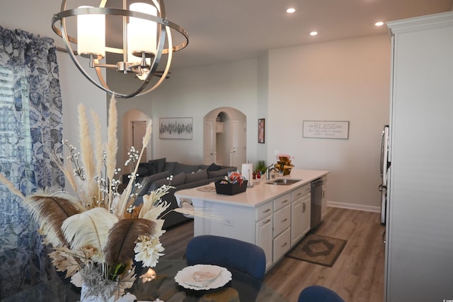 kitchen featuring a center island with sink, white cabinetry, stainless steel dishwasher, a chandelier, and dark hardwood / wood-style floors