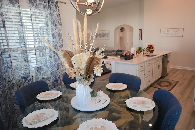 dining room with an inviting chandelier, sink, and light wood-type flooring