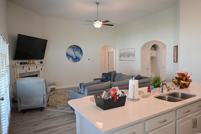 kitchen with hardwood / wood-style floors, sink, white cabinetry, high vaulted ceiling, and ceiling fan