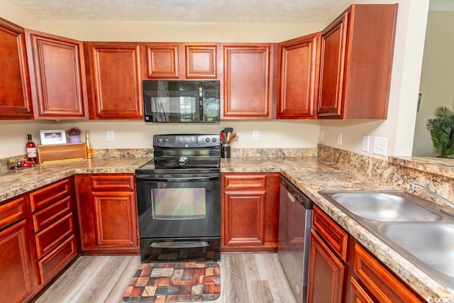 kitchen with light wood-type flooring, a textured ceiling, sink, black appliances, and light stone countertops