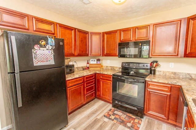 kitchen featuring a textured ceiling, black appliances, light stone countertops, and light hardwood / wood-style flooring