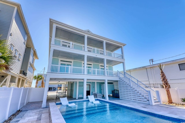 rear view of property with a balcony, a fenced in pool, and a patio