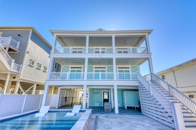 rear view of property featuring a patio, fence, a fenced in pool, a carport, and stairs