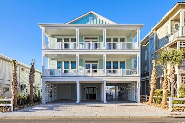 coastal home with a carport, board and batten siding, decorative driveway, and a balcony