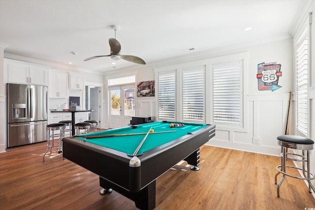 rec room with a wainscoted wall, light wood-type flooring, a decorative wall, billiards, and a ceiling fan