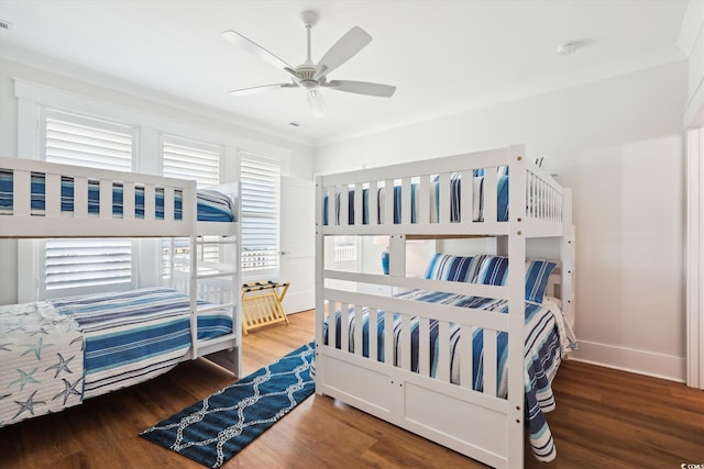 bedroom featuring ceiling fan, visible vents, baseboards, and wood finished floors