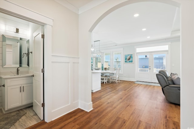 hall with ornamental molding, a sink, wood finished floors, recessed lighting, and arched walkways