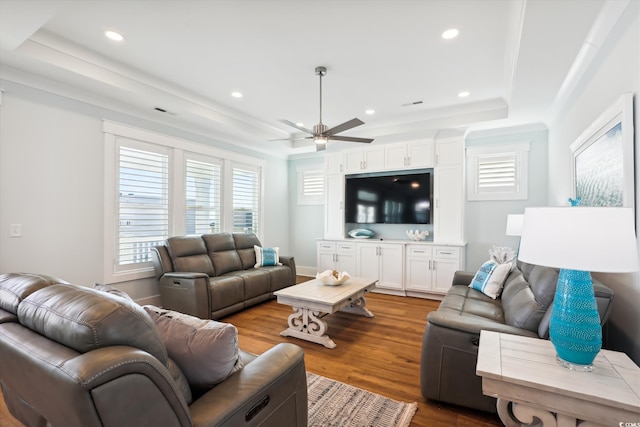 living room with a ceiling fan, wood finished floors, baseboards, a tray ceiling, and recessed lighting