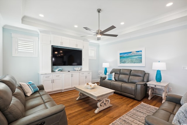 living area with recessed lighting, a raised ceiling, and wood finished floors