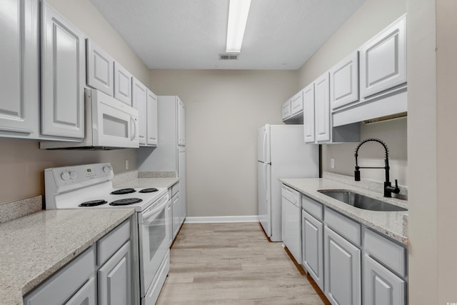 kitchen featuring white appliances, light hardwood / wood-style flooring, sink, light stone countertops, and a textured ceiling