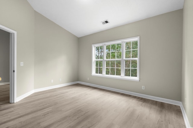 spare room featuring lofted ceiling and light wood-type flooring