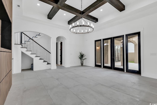 unfurnished living room featuring coffered ceiling, beamed ceiling, a high ceiling, and an inviting chandelier