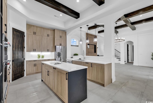 kitchen with light countertops, beamed ceiling, arched walkways, a sink, and light brown cabinetry