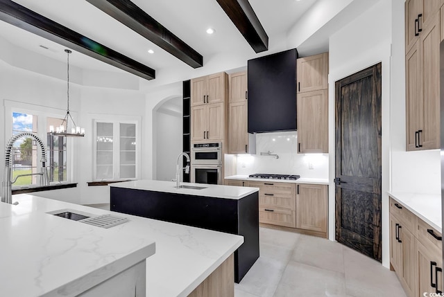 kitchen featuring beamed ceiling, a kitchen island with sink, ventilation hood, stainless steel appliances, and light brown cabinetry