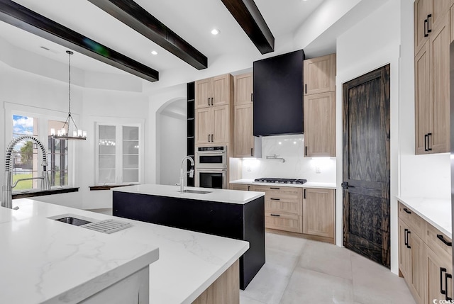 kitchen featuring a center island with sink, gas cooktop, ventilation hood, and light brown cabinets