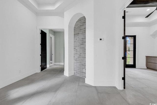 spare room featuring a high ceiling, a raised ceiling, and baseboards