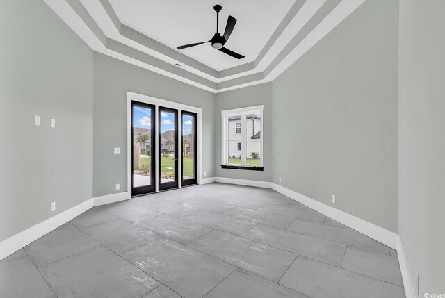 unfurnished room with a raised ceiling, a towering ceiling, baseboards, and ceiling fan