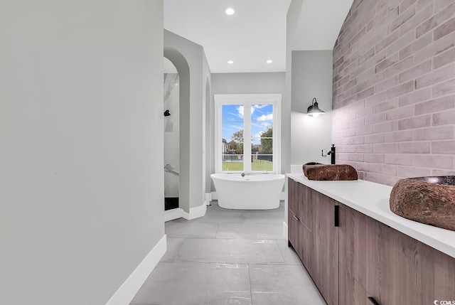 bathroom featuring brick wall, vanity, a bathing tub, and tile patterned floors