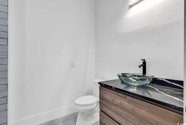 bathroom with toilet, vanity, tile patterned flooring, and baseboards