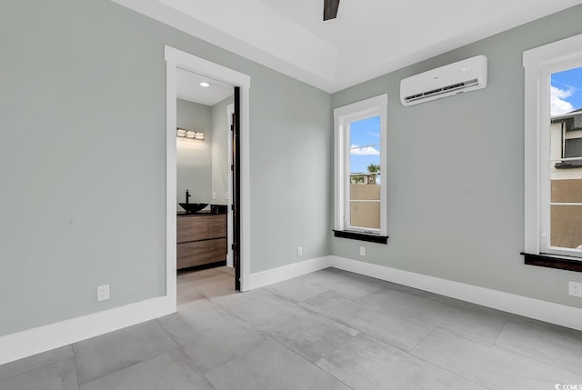 unfurnished bedroom with ceiling fan and a wall mounted air conditioner