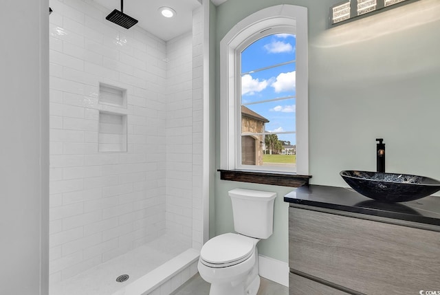 bathroom with tiled shower, vanity, toilet, and a wealth of natural light