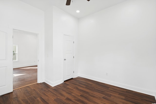 unfurnished room with ceiling fan, a towering ceiling, and dark hardwood / wood-style flooring