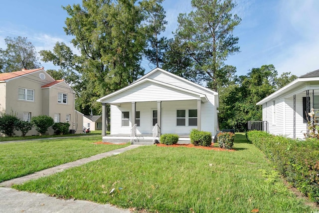 bungalow with cooling unit, covered porch, and a front yard