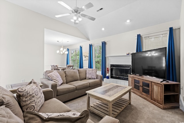 carpeted living room featuring ceiling fan with notable chandelier and vaulted ceiling