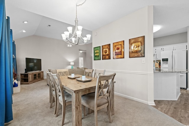 dining area with vaulted ceiling, an inviting chandelier, light carpet, and sink