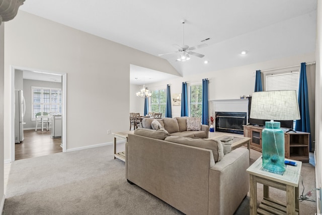 carpeted living room with ceiling fan with notable chandelier, lofted ceiling, and a wealth of natural light