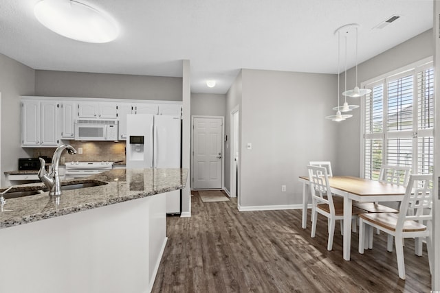 kitchen featuring hanging light fixtures, dark wood-type flooring, white cabinets, white appliances, and light stone countertops