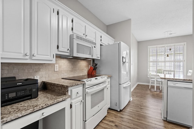 kitchen with white cabinets, light wood-type flooring, light stone countertops, and white appliances