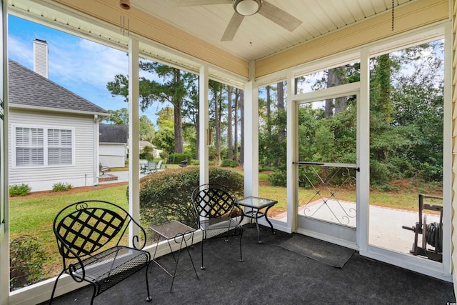 unfurnished sunroom featuring wood ceiling, ceiling fan, and a healthy amount of sunlight