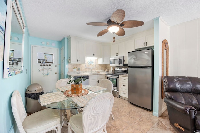 kitchen with decorative backsplash, ceiling fan, appliances with stainless steel finishes, white cabinetry, and sink