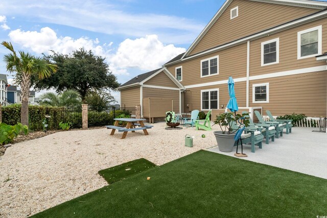 back of property with a patio, a lawn, and an outdoor fire pit