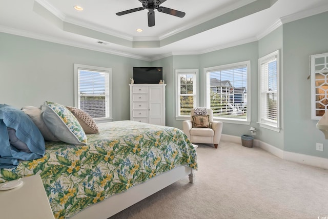 carpeted bedroom featuring ceiling fan, ornamental molding, a tray ceiling, and multiple windows