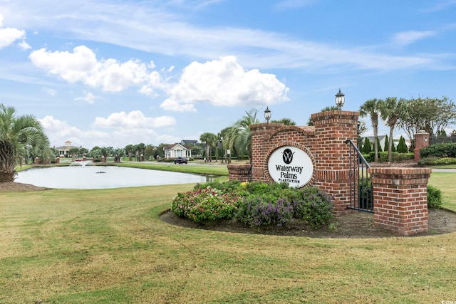 community / neighborhood sign with a water view and a lawn