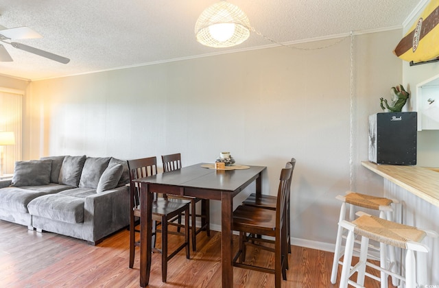 dining room with ceiling fan, a textured ceiling, hardwood / wood-style floors, and crown molding