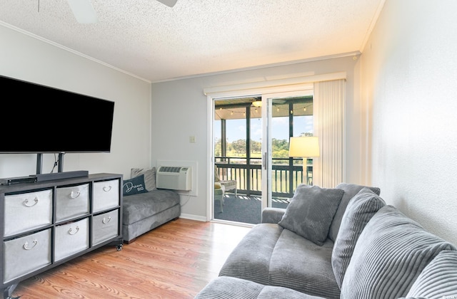 living room featuring a textured ceiling, ceiling fan, light hardwood / wood-style flooring, ornamental molding, and a wall mounted AC