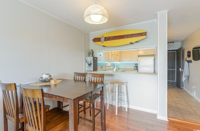 dining area featuring ornamental molding, a textured ceiling, and light hardwood / wood-style floors