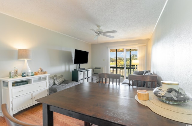 dining room featuring ceiling fan, ornamental molding, a textured ceiling, hardwood / wood-style floors, and a wall unit AC