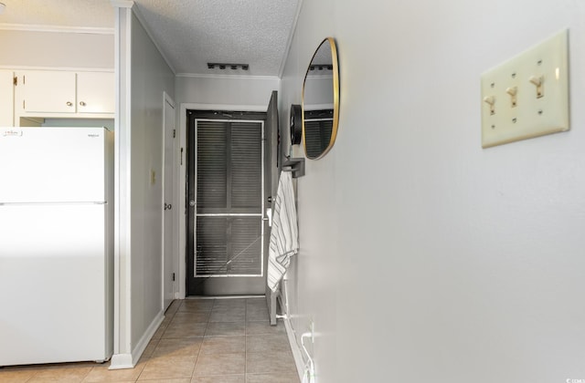 corridor featuring light tile patterned flooring, ornamental molding, and a textured ceiling