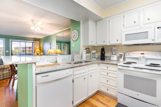 kitchen with light hardwood / wood-style flooring, white appliances, kitchen peninsula, and sink