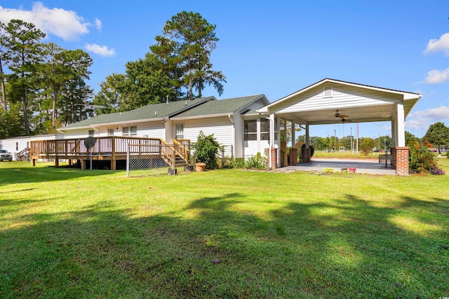 back of property featuring ceiling fan, a deck, a yard, and a carport