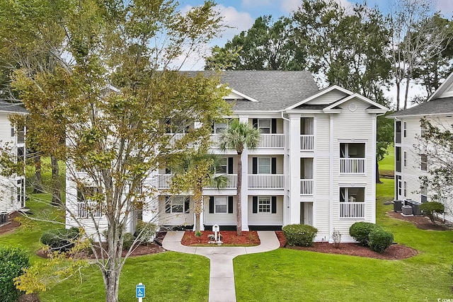 view of front of home featuring central AC unit, a balcony, and a front lawn